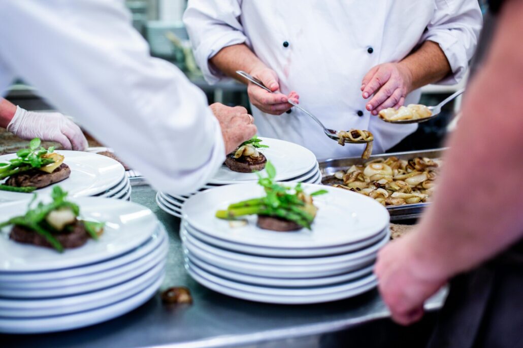 Chefs prepare and plate gourmet dishes in a professional restaurant kitchen.