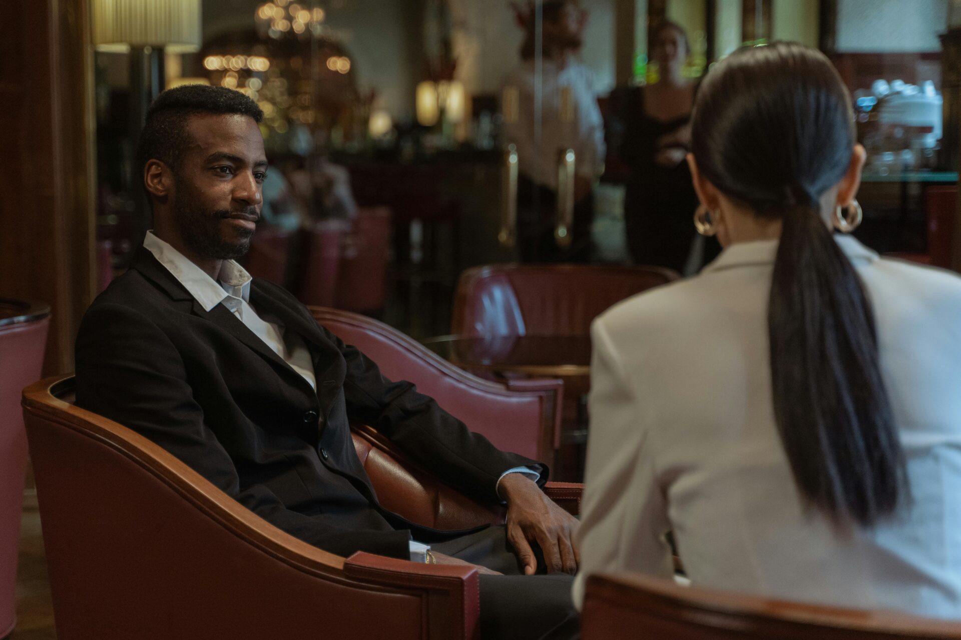 Two professionals engaged in a thoughtful conversation inside an elegant restaurant lobby.